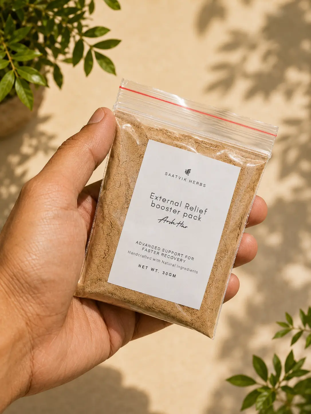 A hand holding the ArshHar external booster pack, a sealed pouch of pale brown powder